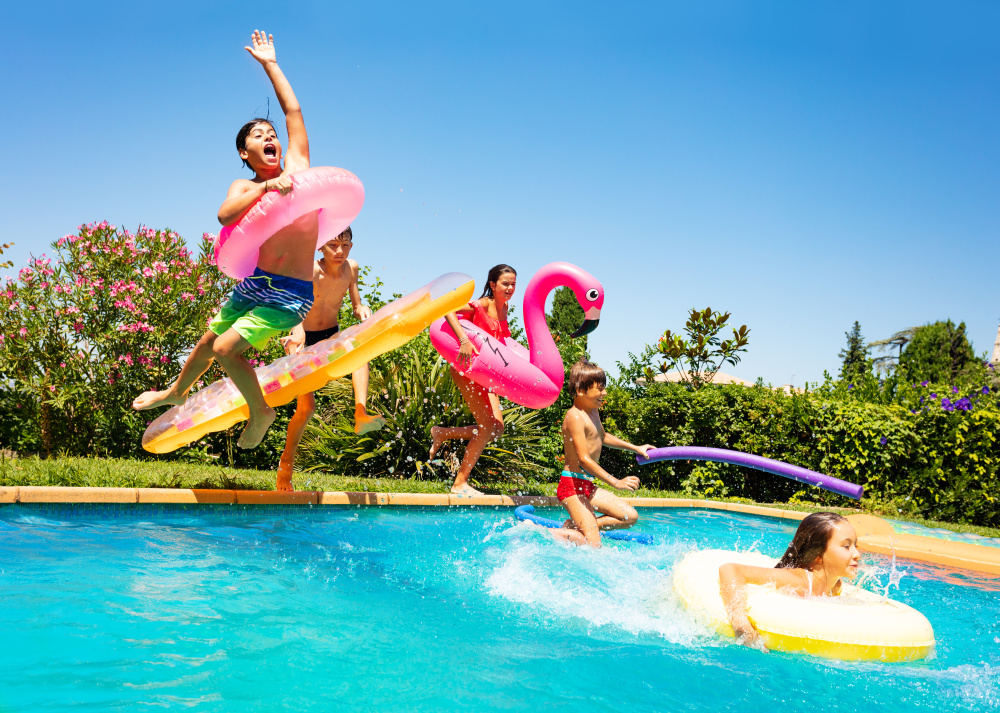 Kids jumping into pool with pool floats