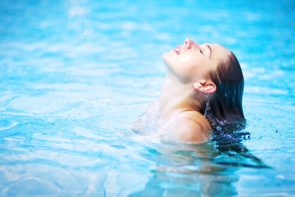 Woman coming up for air in a clear blue pool